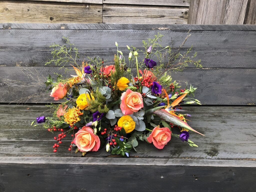 Rouwbloemstuk in oranje en geeltinten. Plukboeket stijl.